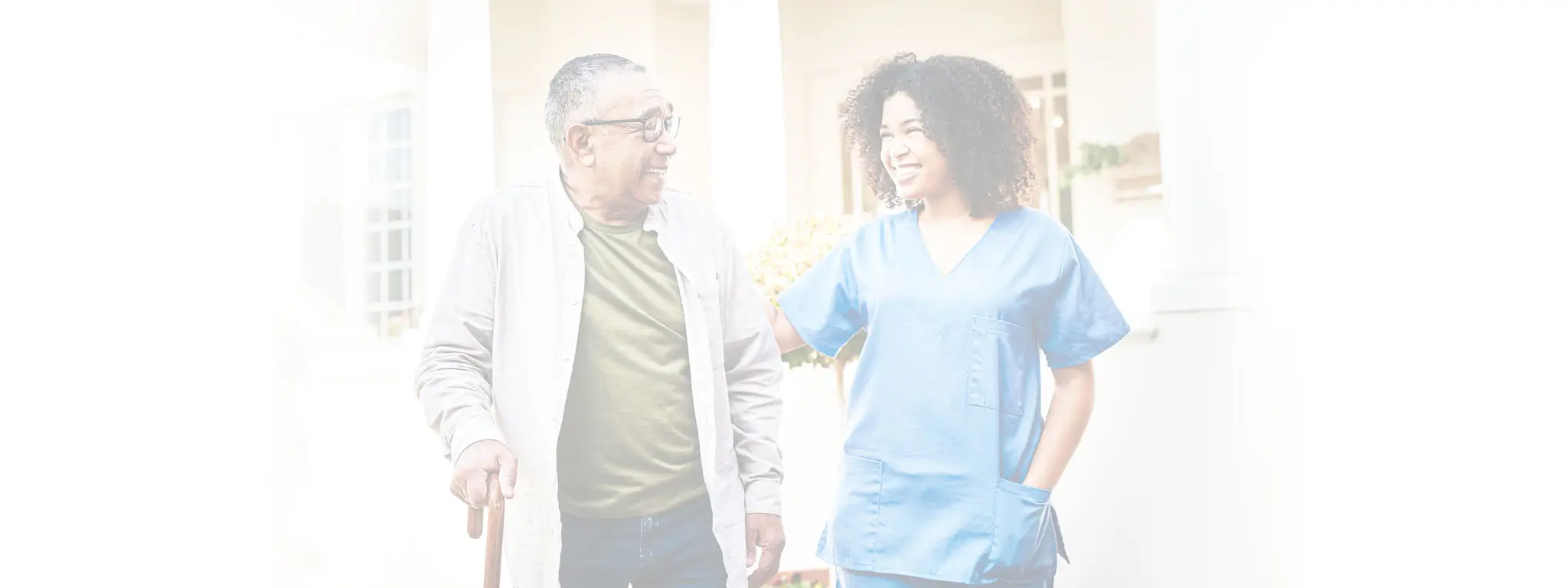 Caregiver with male client using a cane